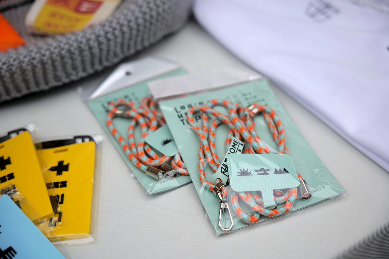 平安符手機墊片掛繩／延伸《空間識別裝置-祝》作品，結合以廣慈生活、文史地理脈絡為題材的趣味短籤詩，貼身書寫當代城市生活脈動，營造鮮明的場域特徵與個性，給予居民旅途平安的祝福意涵。